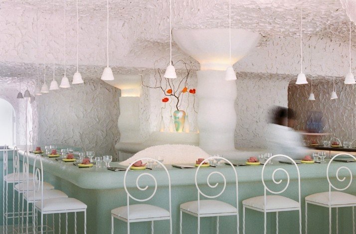 CENTO Raw Bar's interior with white textured walls, pendant lights, and artistic vase decor