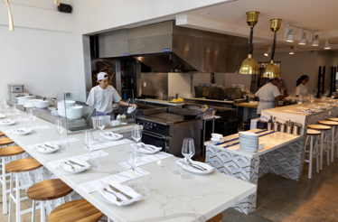 Modern open-kitchen dining room at CENTO Pasta Bar with chefs preparing food.
