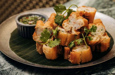 Golden fried bread cubes stacked on a banana leaf, garnished with cilantro and served with dipping sauce at Crying Tiger Chicago.