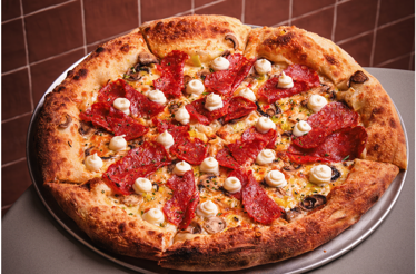 Gourmet pepperoni and mushroom pizza topped with cream swirls from Bar Bucce in Miami, Florida.