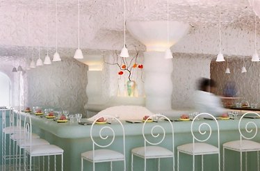 CENTO Raw Bar's interior with white textured walls, pendant lights, and artistic vase decor
