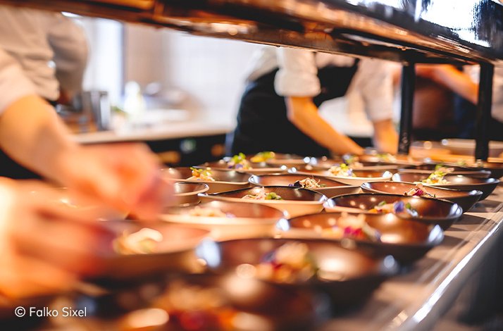 Kitchen table at a JRE Restaurant full of various dishes. © Falko Sixel