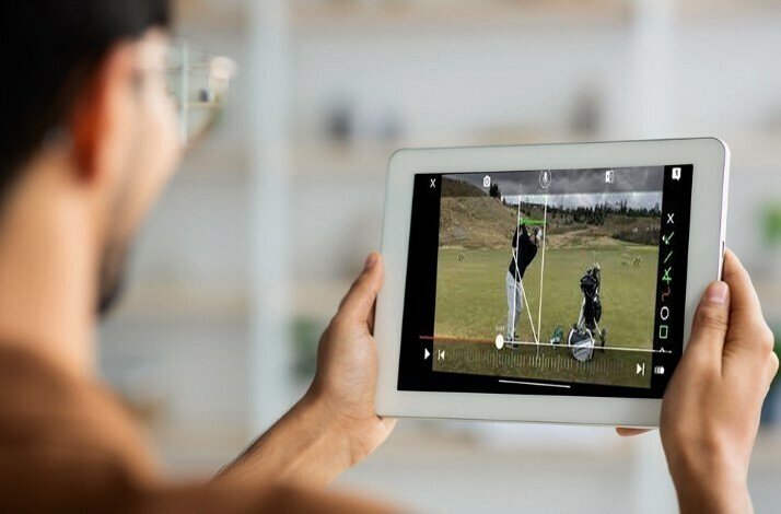 Young man watching the video on golf playing tips from a tablet.