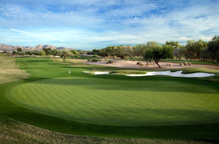 Scottsdale golf course green with flag, sand bunkers, trees, and blue sky.