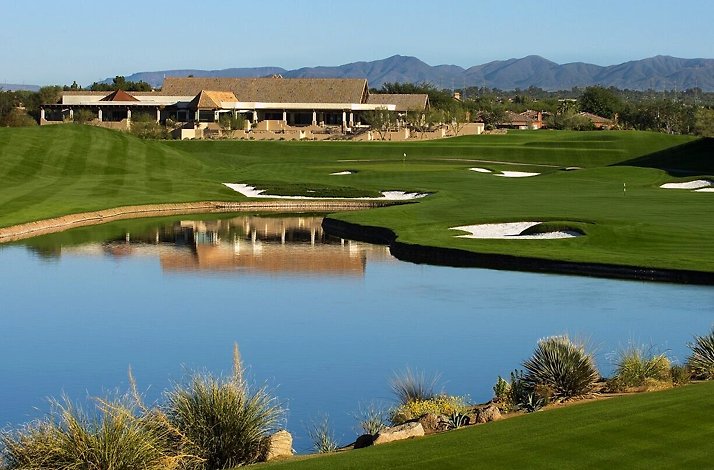 Scottsdale golf course with water, sand bunkers, and clubhouse, mountains in distance.