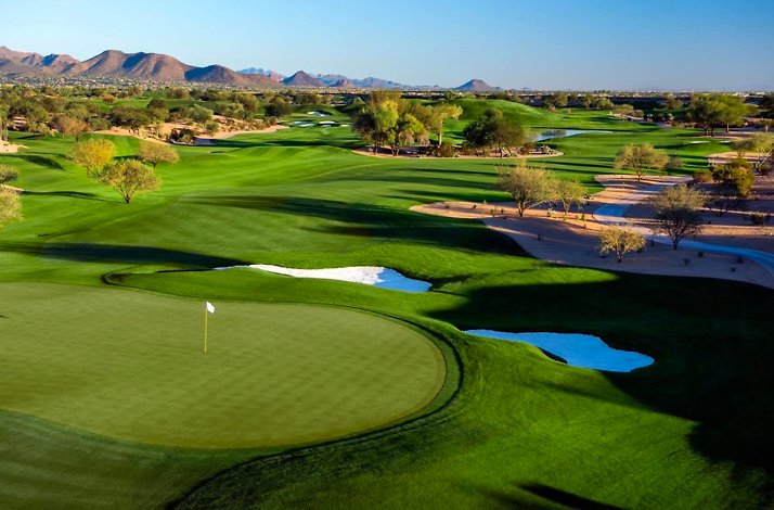 Scottsdale golf course with water, sand bunkers, and clubhouse, mountains in distance.