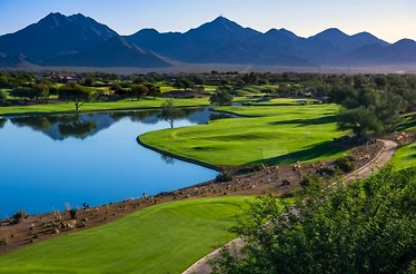 Scottsdale lush golf course with water features, trees, and mountain backdrop.