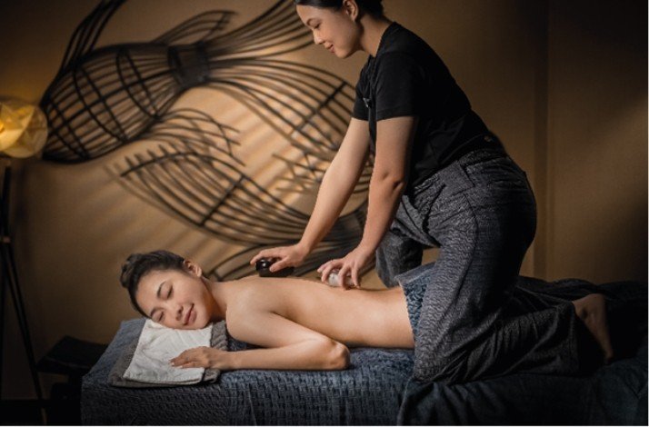 Interior of Thann Sanctuary, featuring a worker giving a massage to a client lying on a massage table.