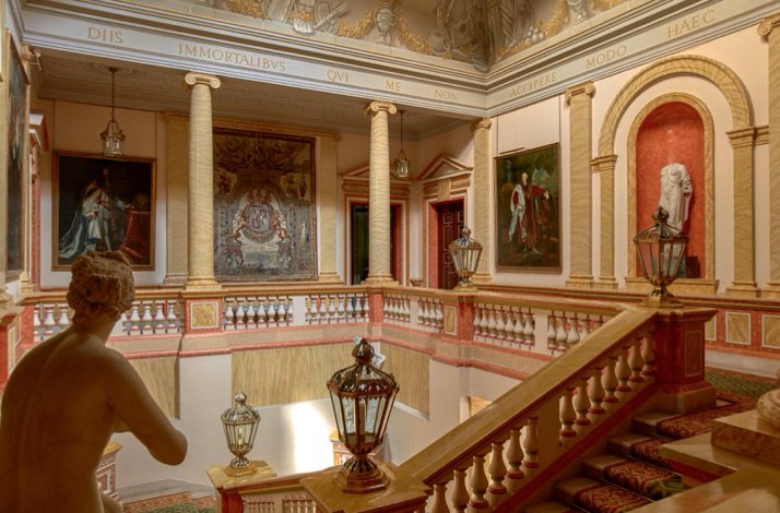 Interior of the Palacio de Liria, featuring a grand staircase and large framed artworks decorating the walls