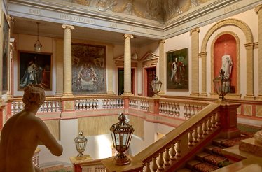 Interior of the Palacio de Liria, featuring a grand staircase and large framed artworks decorating the walls