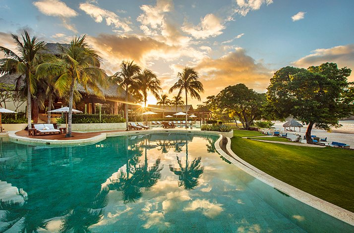 Sun shining over palms trees and swimming pool at Preferred Hotels & Resorts.