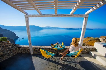 A woman sitting by the table on the terrace with a sea view