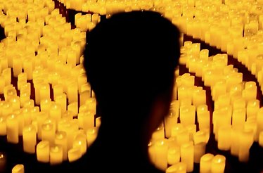 A silhouette of a person in a room full of candles at tribute concert to Ludovico Einaudi.