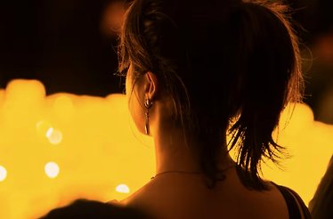 View from behind of a person lit up by candles at a Candlelights event.