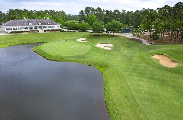 View at TPC Myrtle Beach’s clubhouse surrounded by the golf courses landscape with a pond at the front.
