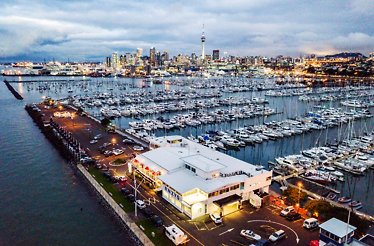Aerial view of Westhaven Marina with countless yachts, Auckland skyline, and RNZYS building at twilight