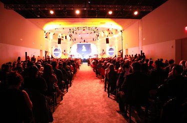 Audience watching Latin Grammys in a crowded room.