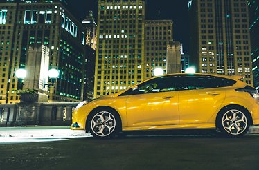 A yellow rental car photographed on a street at night