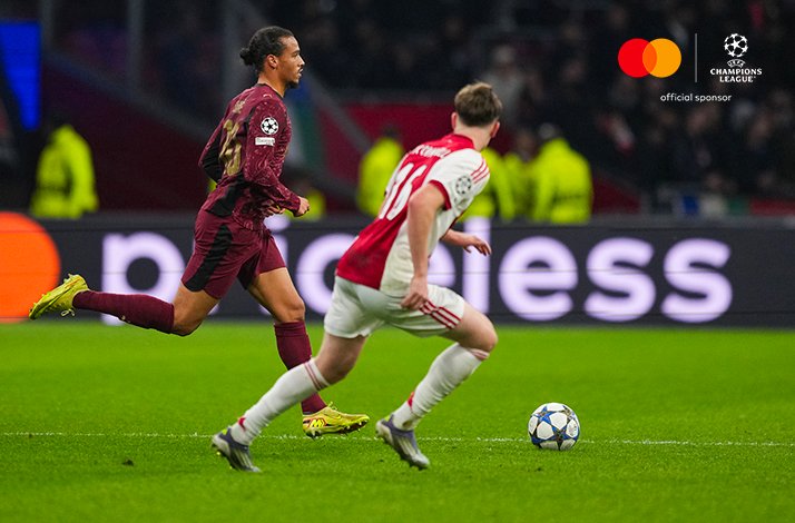 Galatasaray A.S. and AFC Ajax players racing for the ball during UEFA Champions League 2025/26 league phase MD4, Mastercard logo and UEFA Champions League 'official sponsor' badge visible in the upper-right corner.