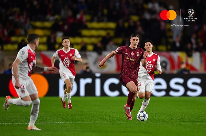 Galatasaray player carries the ball as Monaco defenders close in during a UEFA Champions League game.
