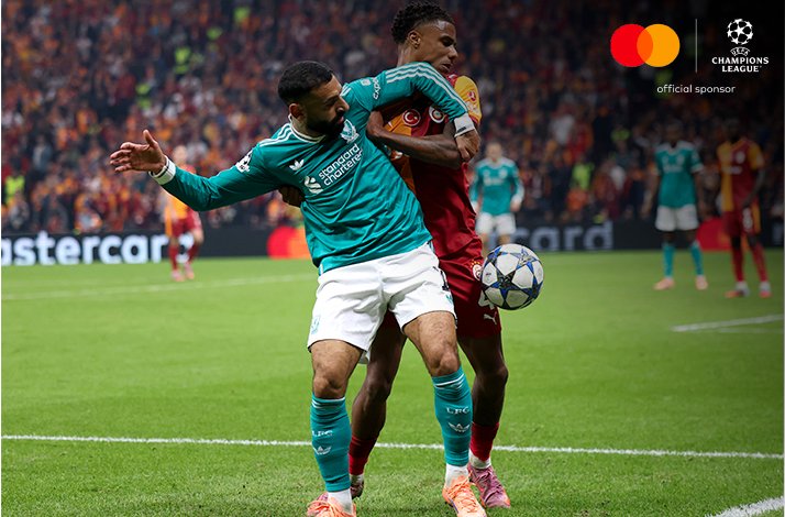 Liverpool FC and Galatasaray A.S. players battling for possession during UEFA Champions League 2025/26 match, Mastercard logo and UEFA Champions League 'official sponsor' badge visible in the upper-right corner.