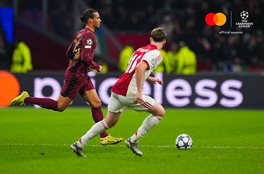 Galatasaray A.S. and AFC Ajax players racing for the ball during UEFA Champions League 2025/26 league phase MD4, Mastercard logo and UEFA Champions League 'official sponsor' badge visible in the upper-right corner.