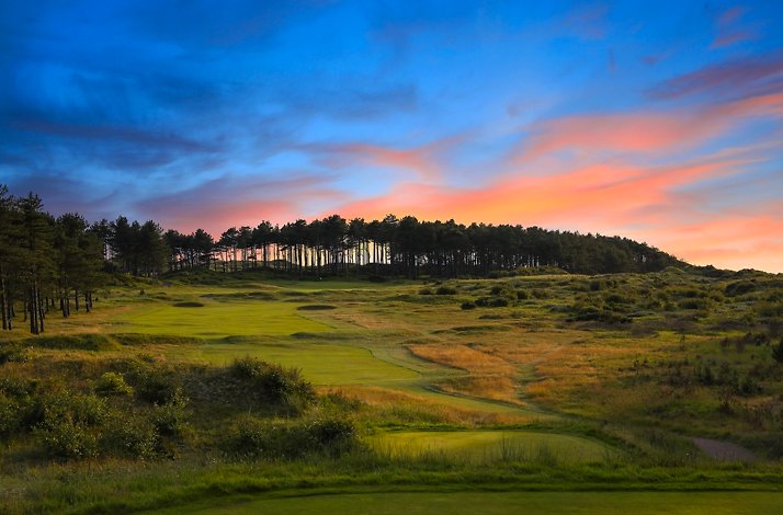 Formby Golf Club fairway with trees and dunes at sunset.