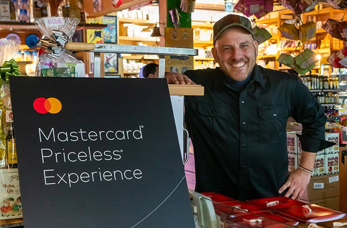 Afrim Pristine, chef at Toronto's Cheese Boutique, poses beside Mastercard Priceless sign.