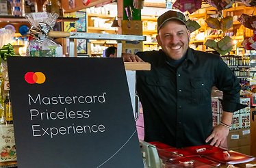 Afrim Pristine, chef at Toronto's Cheese Boutique, poses beside Mastercard Priceless sign.