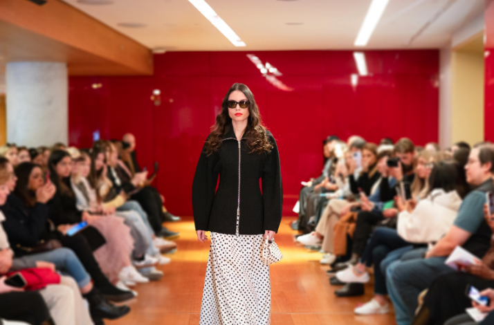 A female model walking on the runway, wearing a black jacket over a polkadot dress at Galeries Lafayette Paris Haussmann.