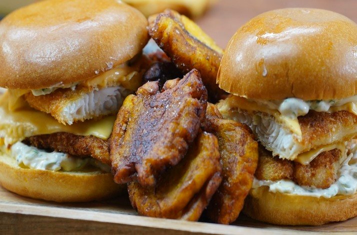 Delicious sliders topped with fried plantains and creamy sauce, served on soft buns alongside crispy plantain slices.