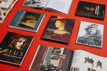 Art books about Rembrandt orderly set on a red surface.