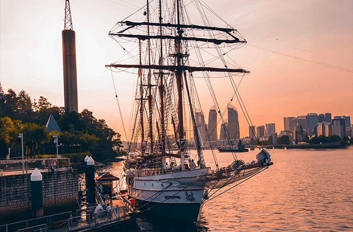 View of the Royal Albatross at a port with a city skyline on the background.