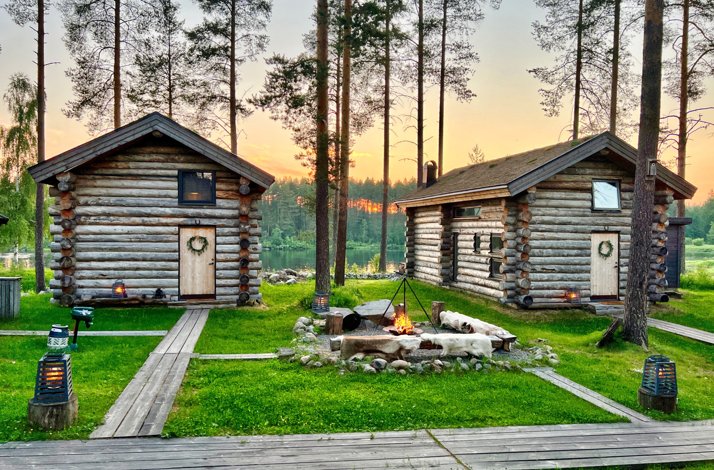 Escape to northern Sweden's Lapland for a summer or fall adventure: In Överstbyn, Sweden Log cabins in a forest with wooden paths and a bonfire