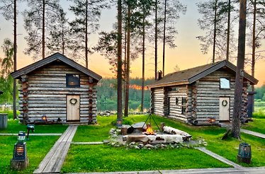 Log cabins in a forest with wooden paths and a bonfire