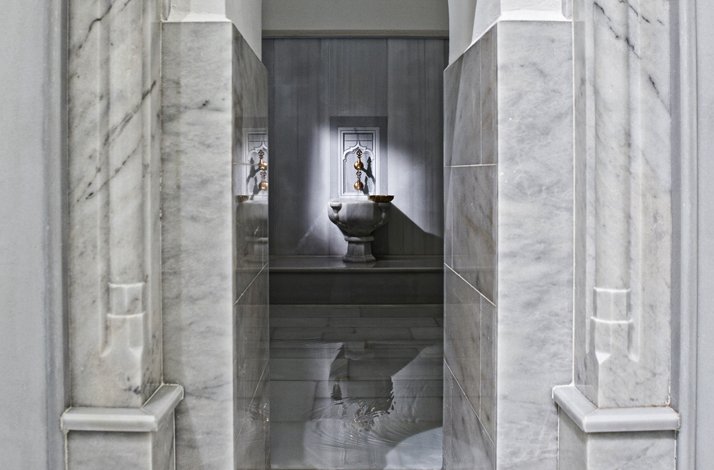 A marble hallway in Hürrem Sultan Hammam with a traditional fountain at the end.