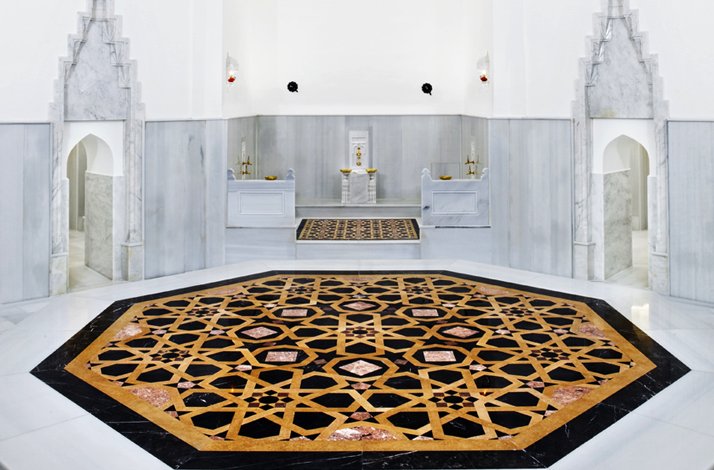 The central bathing hall of Hürrem Sultan Hammam with marble architecture and an ornate geometric floor.