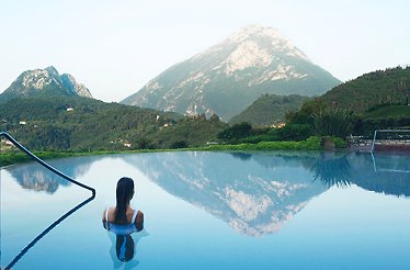 A woman relaxes in a pool with a scenic mountain backdrop.