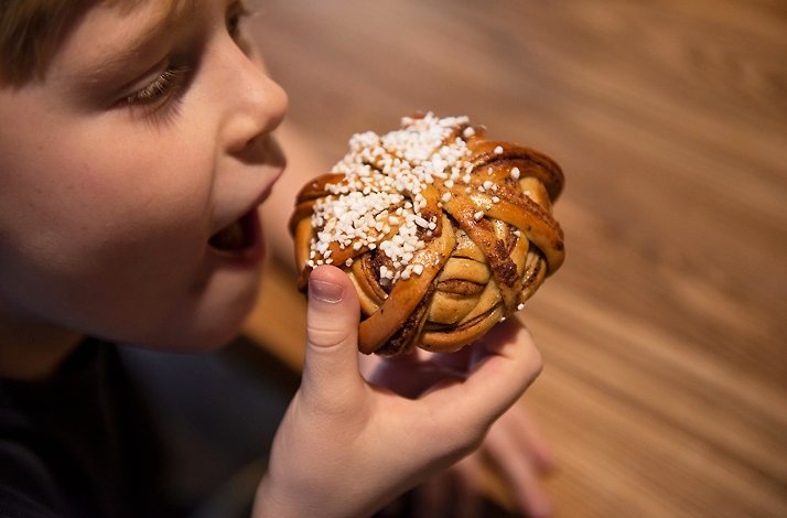 Boy enjoys traditional Swedish fika basket cinnamon buns.