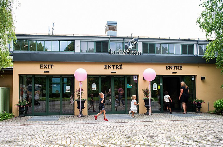 The entrance of  Junibacken’s restaurant decorated with pink balloons and children running around happily. 