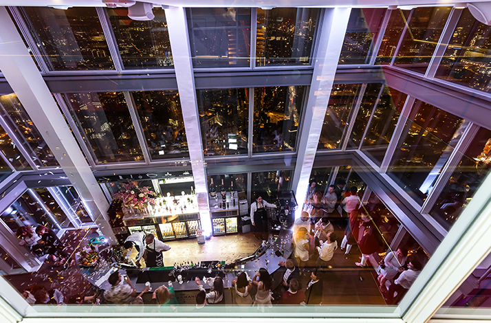 High-angle view of the crowded champagne bar inside The Shard observation deck at night in London, England.