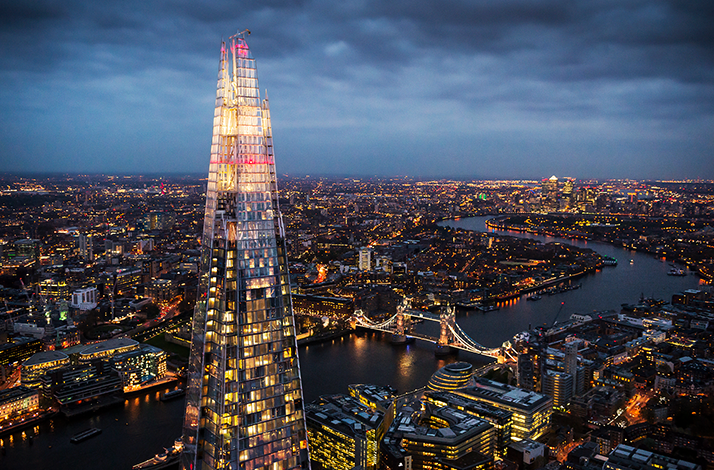The Shard skyscraper overlooking Tower Bridge and the River Thames at night in London, England.