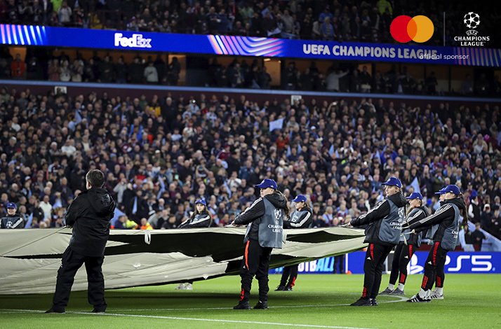 People on a football field holding a banner with an UEFA Champions League logo before a UEFA Champions League match