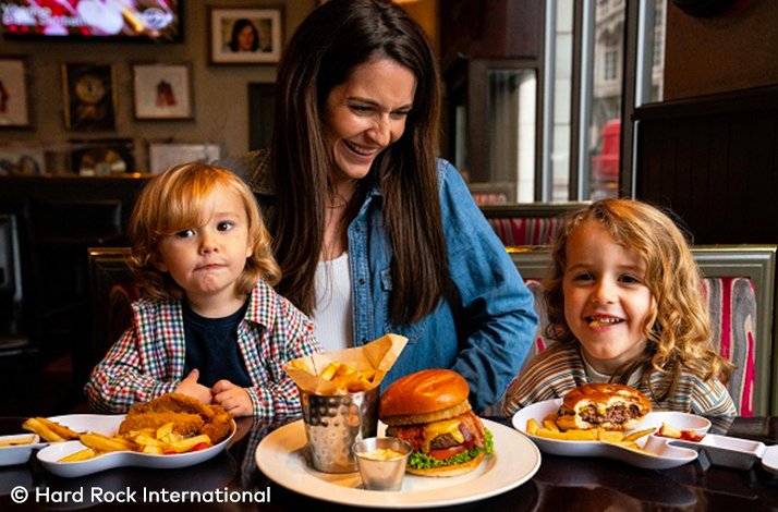 A parent and two kids enjoying a meal of burgers and French fries at the Hard Rock Cafe. © Hard Rock International.