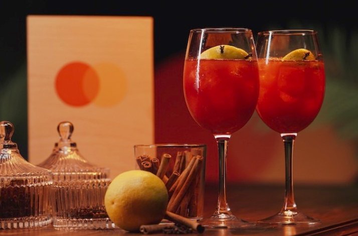 Two glasses of Mediterranean Sangria garnished with cinnamon with the Mastercard logo visible in the background.