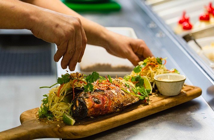 A hand seasoning on fish dish cooked with noodles.