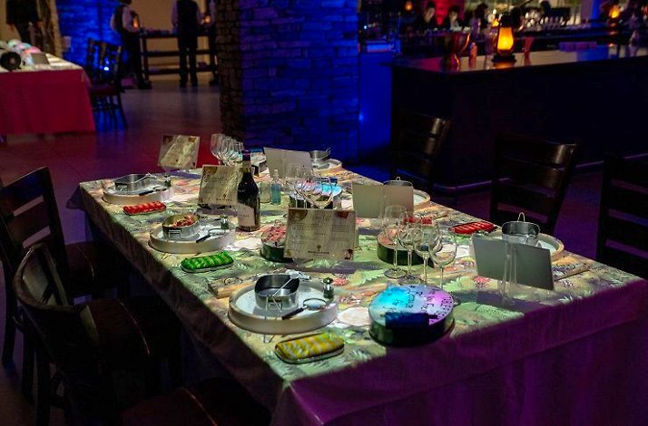 A table adorned with a vibrant tablecloth and neatly arranged place settings for a festive gathering.