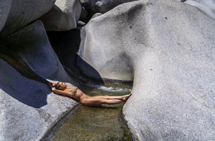 A woman relaxes in a narrow stream surrounded by granite rock formations at Cañón de la Zorra in Mexico's Sierra de la Laguna.