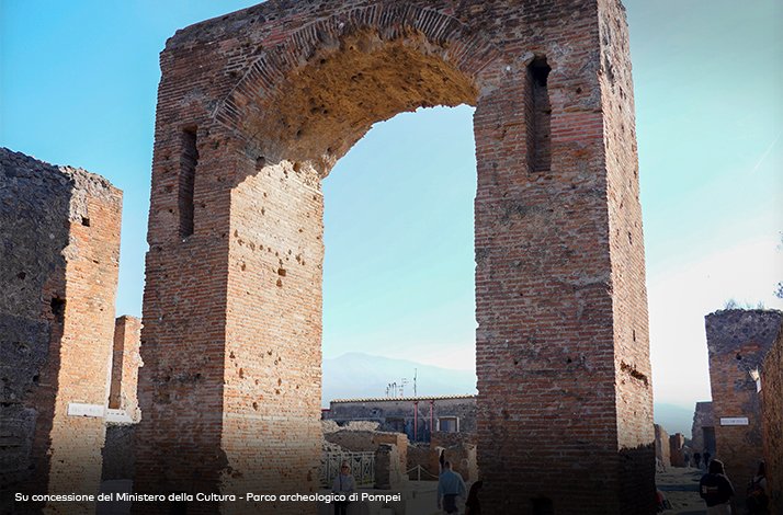 The brick archway of the Arch of Caligula in Pompeii, Italy, with Mount Vesuvius in the background.