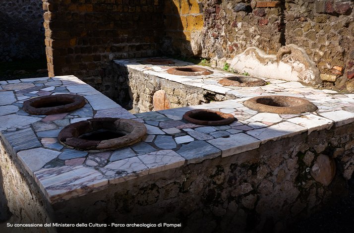 Marble-topped counter of a thermopolium in Herculaneum, Italy, with embedded earthenware jars for hot food.